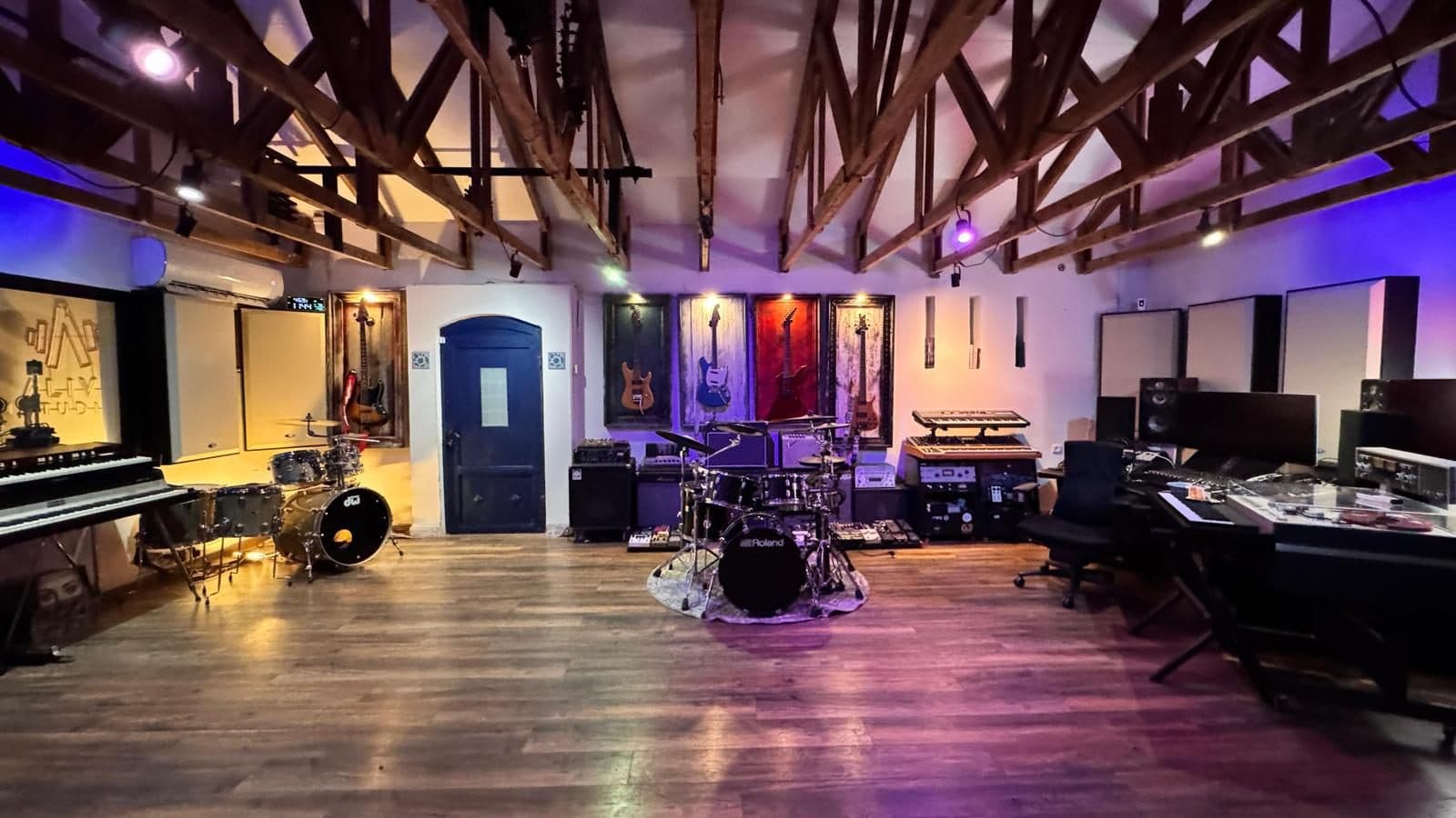 The live room — wood trusses, DW kit, guitar wall and stage lighting