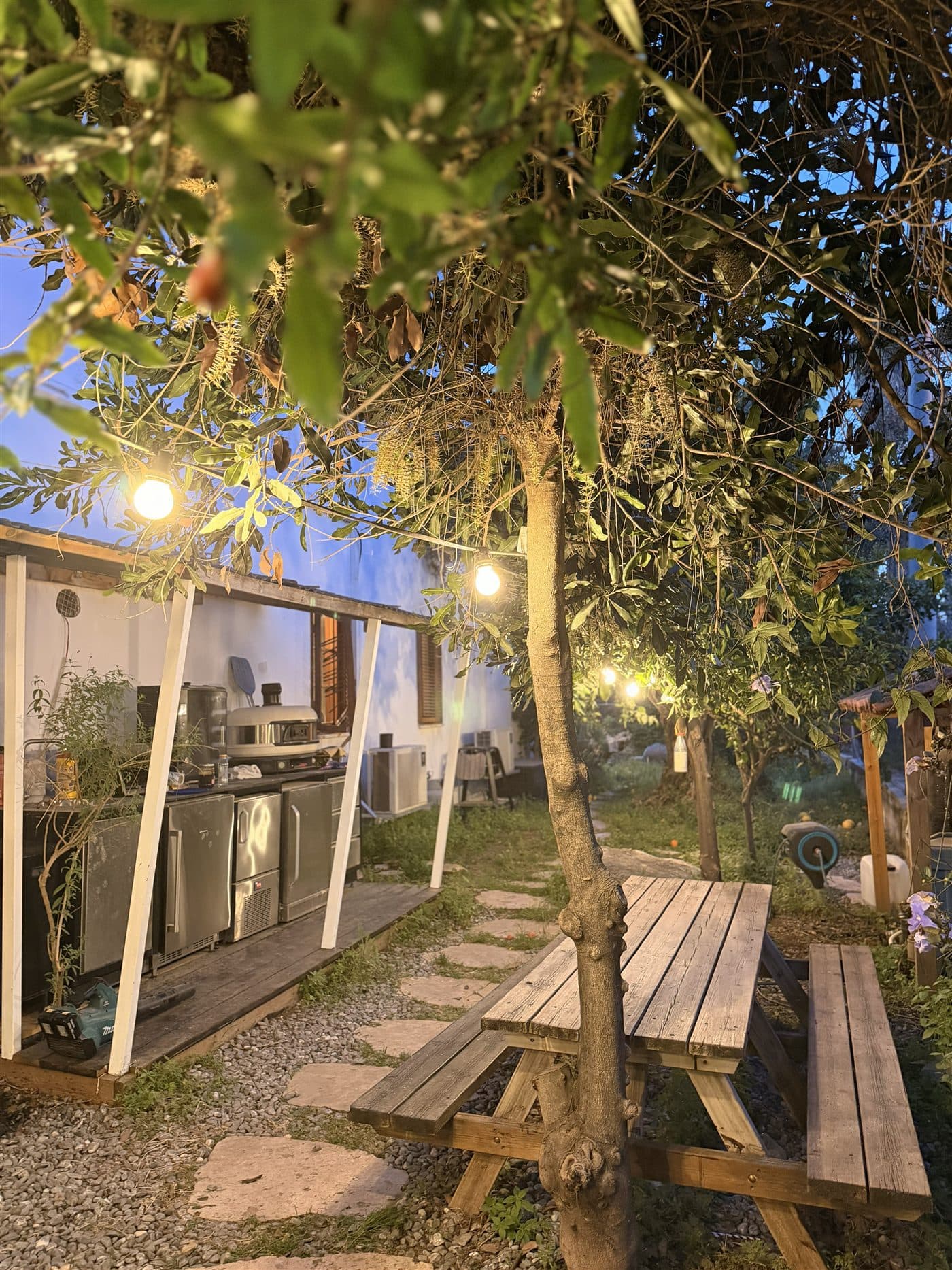 The outdoor kitchen and BBQ under string lights at dusk