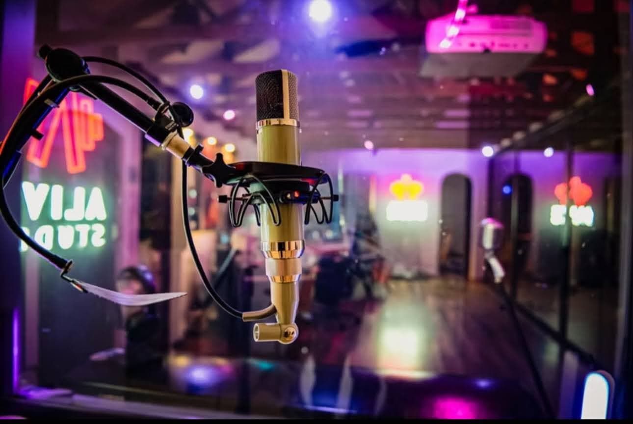 A gold condenser mic with the Alive Studio neon behind